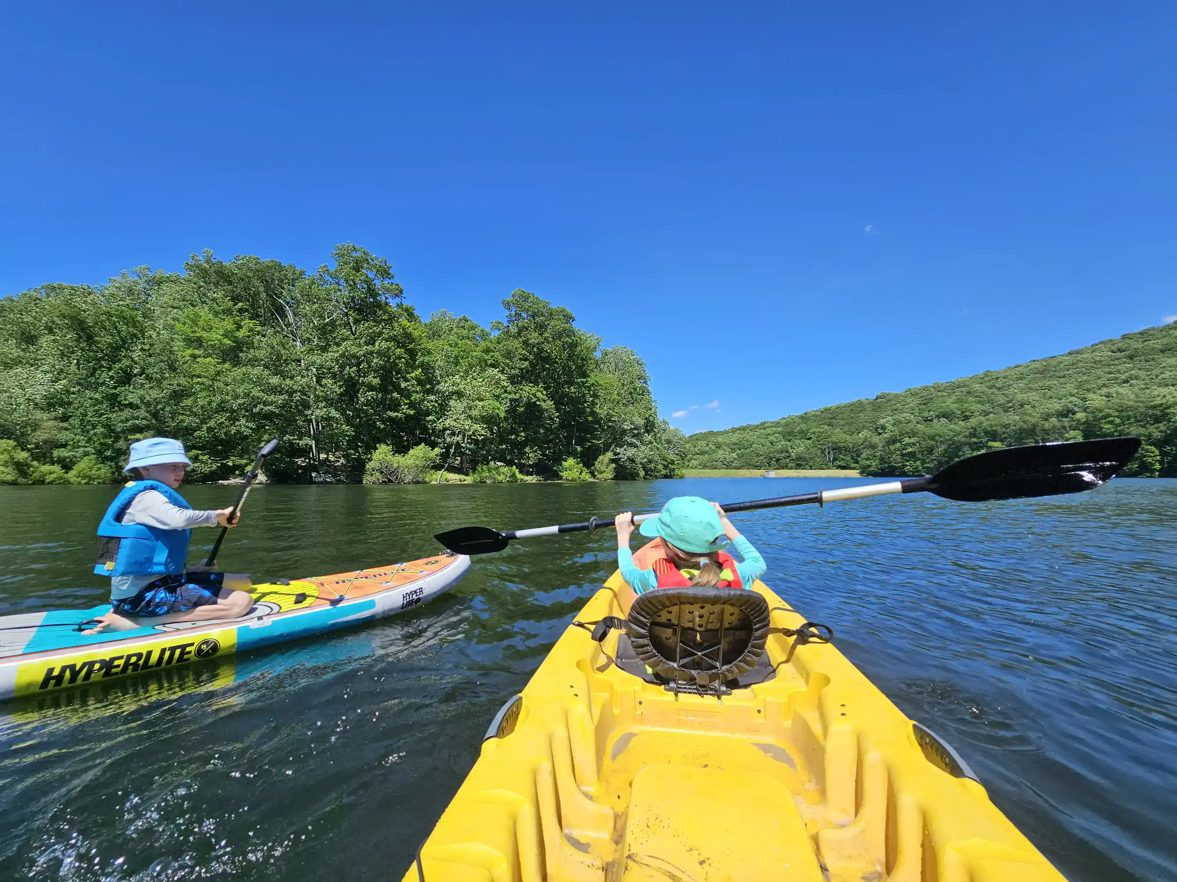 Kids on paddle water craft in a lake.